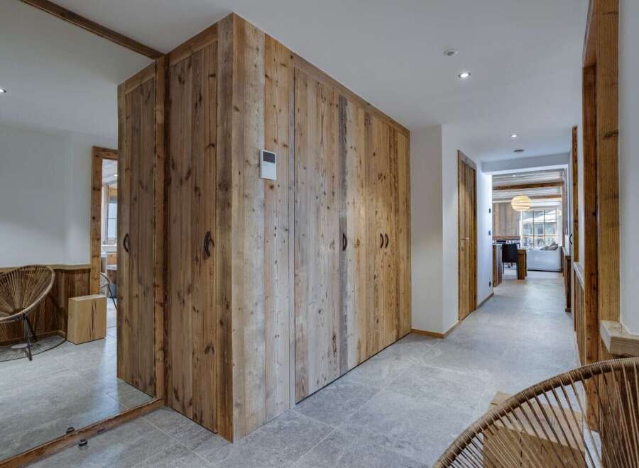 This stunning chalet boasts a spacious hallway with rustic wooden storage and sleek grey tile flooring.