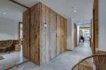 This stunning chalet boasts a spacious hallway with rustic wooden storage and sleek grey tile flooring.
