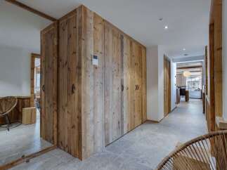This stunning chalet boasts a spacious hallway with rustic wooden storage and sleek grey tile flooring.