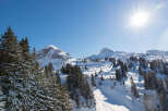 Sun-drenched snowy mountain peaks and slopes offer breathtaking views.
