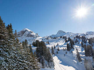 Sun-drenched snowy mountain peaks and slopes offer breathtaking views.