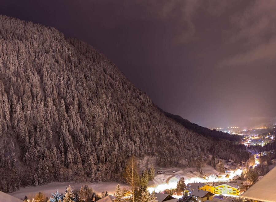 Nestled in a snow-covered mountainside, this charming chalet offers breathtaking night views of the illuminated village below.