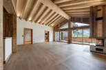 Experience luxury mountain living in this stunning chalet featuring a grand vaulted ceiling with exposed wooden beams and a cozy stone fireplace.