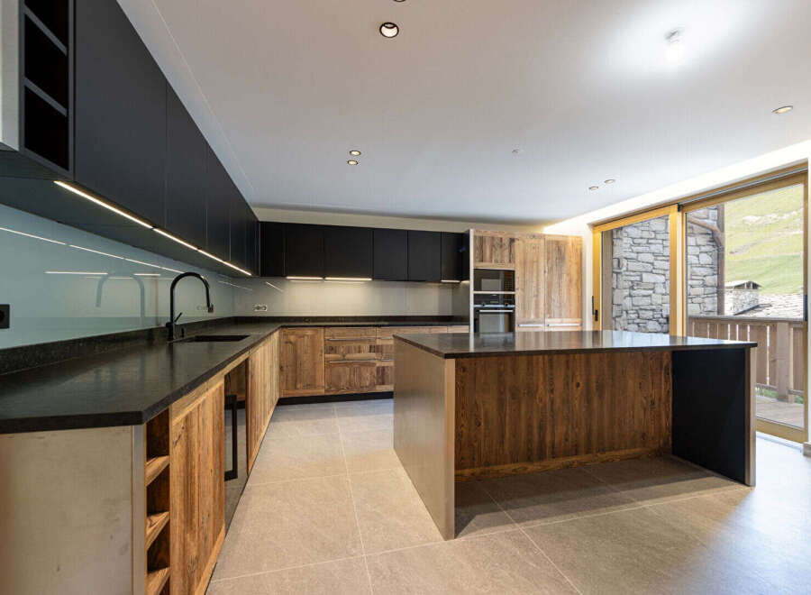 Experience modern mountain living in this stunning kitchen featuring sleek black cabinetry contrasted with rustic wooden accents.