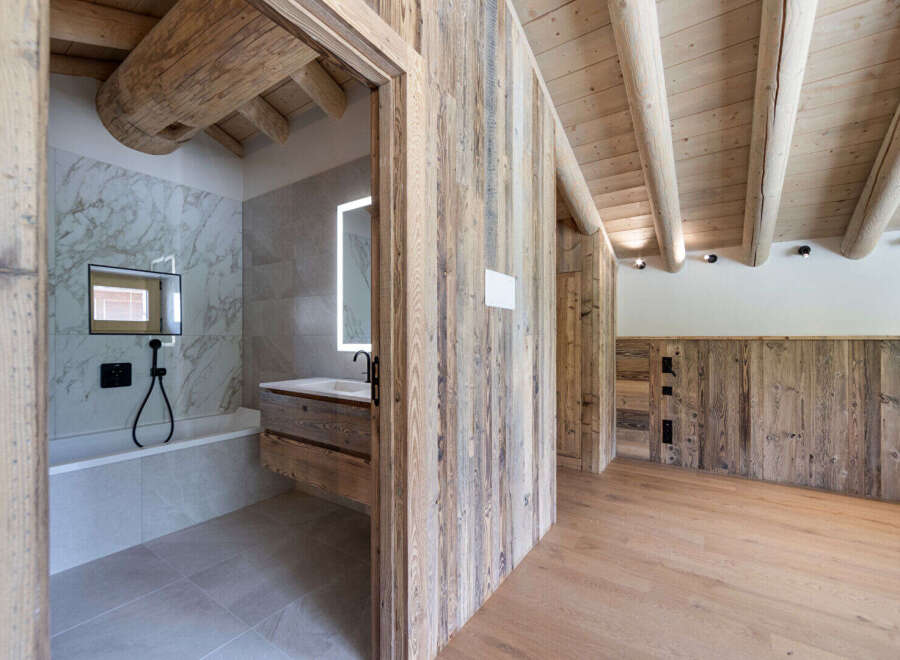 Experience rustic luxury in this stunning bathroom featuring a deep soaking tub and a modern vanity with a backlit mirror.