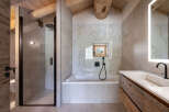 Experience luxury in this modern mountain bathroom, featuring a sleek walk-in shower with a rainfall showerhead and a deep soaking bathtub.