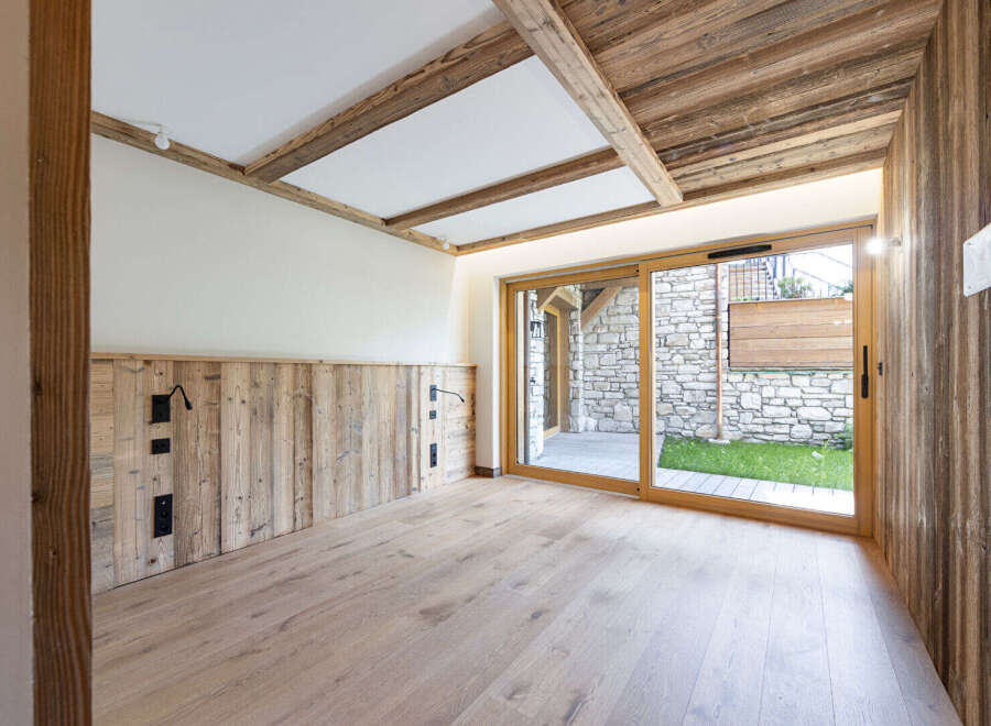Experience rustic charm in this beautifully designed room featuring natural wood paneling on the walls and ceiling, complemented by exposed wooden beams.