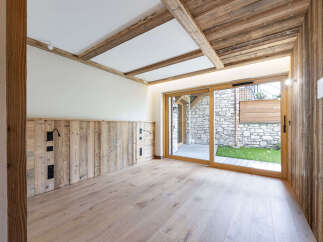 Experience rustic charm in this beautifully designed room featuring natural wood paneling on the walls and ceiling, complemented by exposed wooden beams.