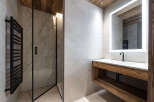Experience modern luxury in this stunning bathroom featuring a sleek glass-enclosed shower with marble-patterned tiles and a black heated towel rack.