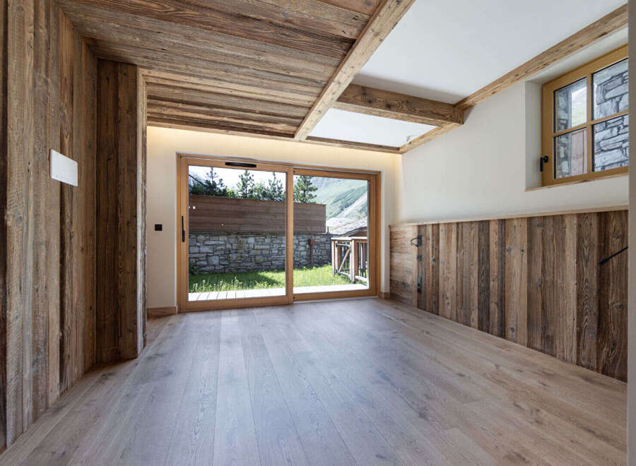 Experience rustic charm and modern comfort in this beautifully appointed room, featuring natural wood paneling on the walls and ceiling, complemented by a light wood floor.
