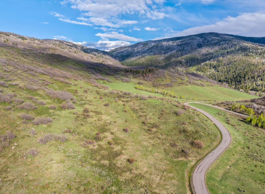This stunning property boasts a scenic winding road leading through a picturesque landscape of rolling hills and lush greenery.