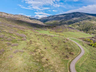 This stunning property boasts a scenic winding road leading through a picturesque landscape of rolling hills and lush greenery.