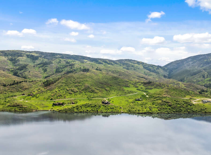 Luxury mountain lakefront homes nestled on sprawling green hillsides.