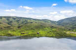 Luxury mountain lakefront homes nestled on sprawling green hillsides.