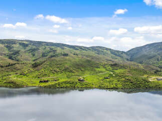 Luxury mountain lakefront homes nestled on sprawling green hillsides.