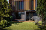 Modern house with a sleek design and large windows, showcasing a beautiful garden with lush green grass and stylish outdoor furniture.
