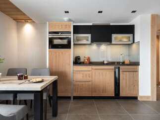 This stunning apartment boasts a modern, fully equipped kitchen with sleek wooden cabinetry and integrated appliances.
