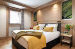 This stunning bedroom boasts a king-size bed with plush bedding, a cozy mustard yellow throw, and a wooden headboard.