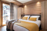This stunning bedroom boasts a cozy wooden interior, complete with a plush bed dressed in luxurious linens and a warm-toned throw.