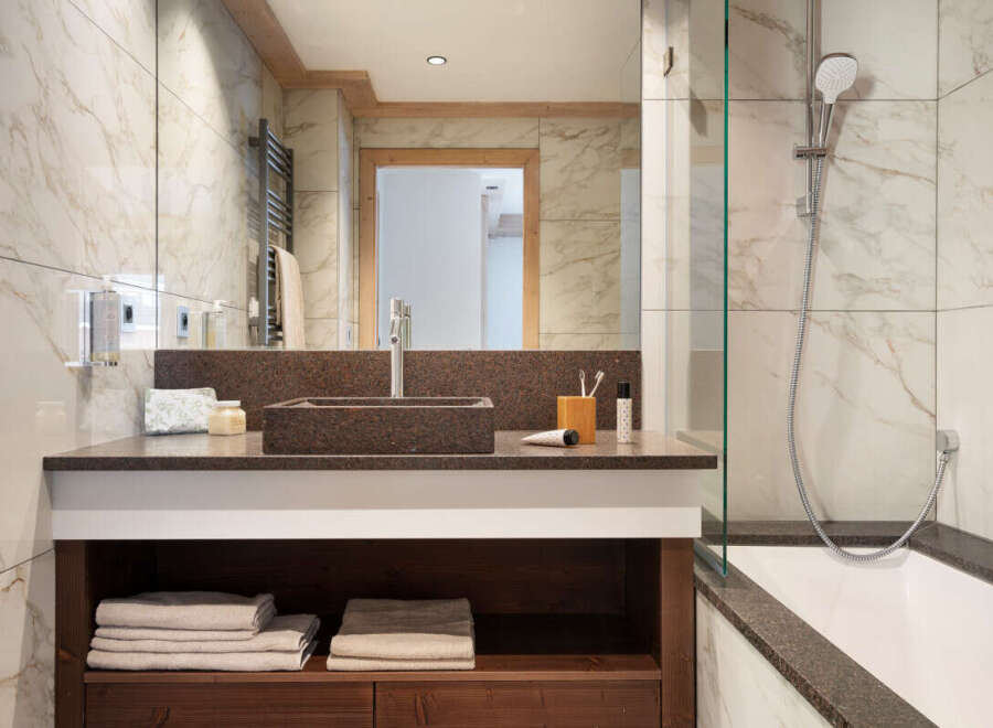 This luxurious bathroom boasts a spacious vanity with dark brown countertop and wooden shelving, providing ample storage.