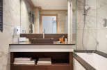 This luxurious bathroom boasts a spacious vanity with dark brown countertop and wooden shelving, providing ample storage.