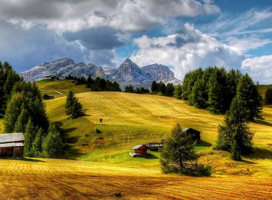 Discover the breathtaking beauty of this mountain landscape, featuring charming wooden cabins nestled amidst rolling hills.