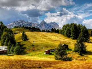 Discover the breathtaking beauty of this mountain landscape, featuring charming wooden cabins nestled amidst rolling hills.