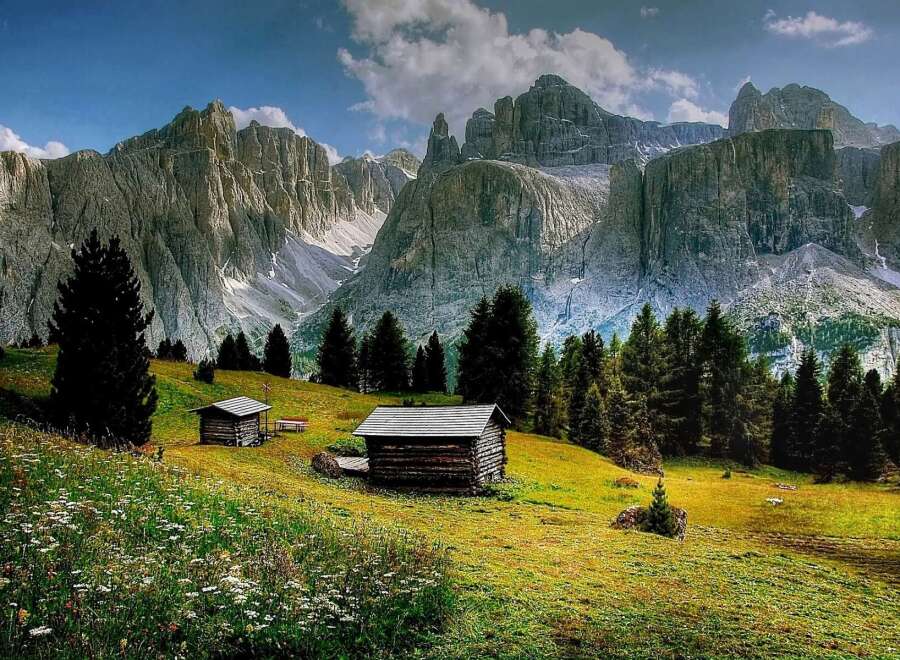 Discover the tranquility of this stunning mountain landscape, featuring charming wooden cabins nestled amidst lush greenery.
