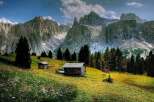 Discover the tranquility of this stunning mountain landscape, featuring charming wooden cabins nestled amidst lush greenery.