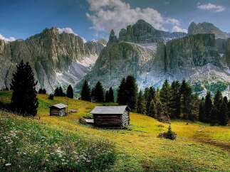 Discover the tranquility of this stunning mountain landscape, featuring charming wooden cabins nestled amidst lush greenery.