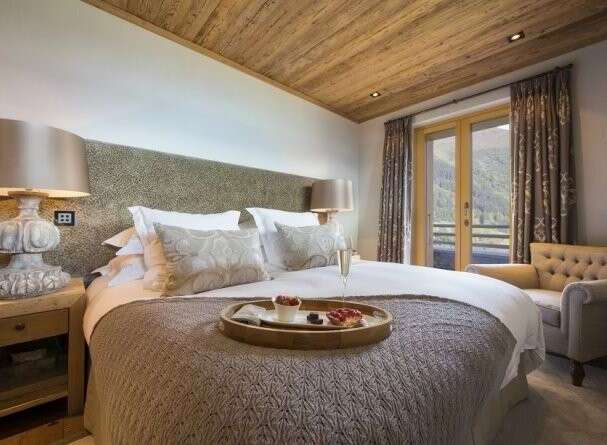 Experience luxury in this stunning bedroom, featuring a cozy bed and a charming seating area.