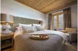 Experience luxury in this stunning bedroom, featuring a cozy bed and a charming seating area.