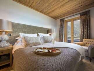 Experience luxury in this stunning bedroom, featuring a cozy bed and a charming seating area.