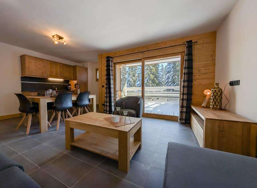 This stunning apartment boasts a spacious open-plan living area with floor-to-ceiling windows offering breathtaking views of the snowy landscape.