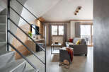 This stunning apartment boasts a spacious living area with a comfortable grey sofa, perfect for relaxing after a day on the slopes.