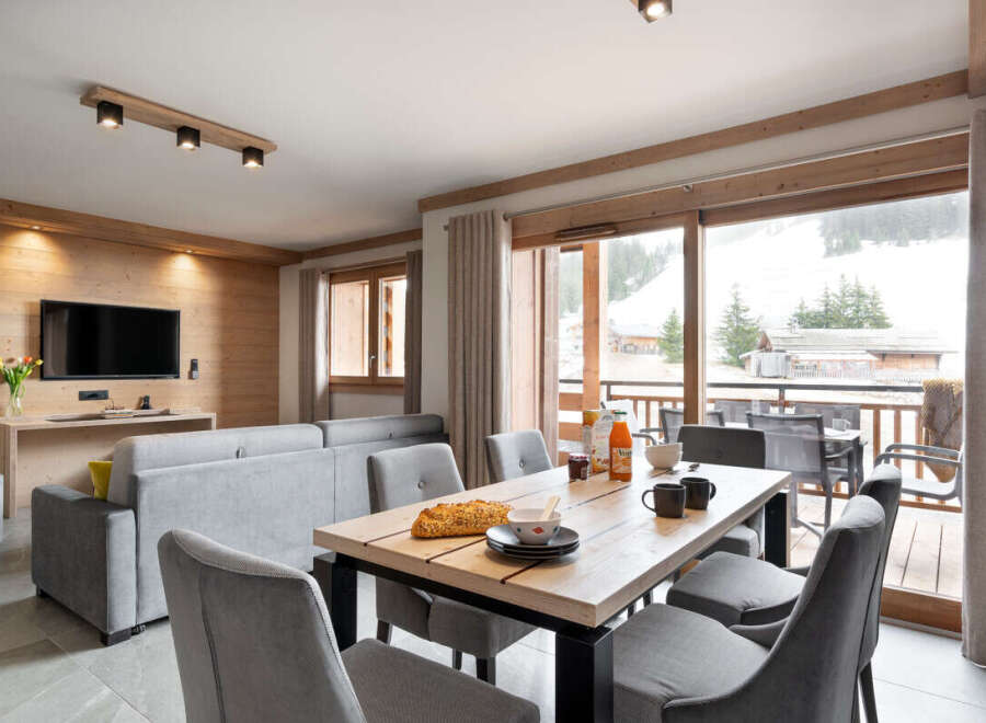 This stunning apartment boasts a spacious open-plan living area with floor-to-ceiling windows offering breathtaking views of the snowy mountains.