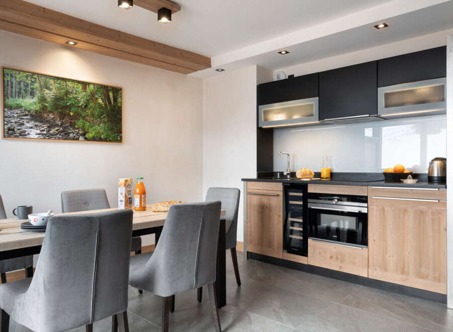 This stunning apartment boasts a modern, fully equipped kitchen with sleek black and light wood cabinetry, perfect for preparing delicious meals.