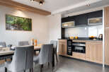 This stunning apartment boasts a modern, fully equipped kitchen with sleek black and light wood cabinetry, perfect for preparing delicious meals.