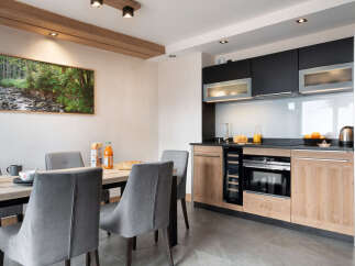 This stunning apartment boasts a modern, fully equipped kitchen with sleek black and light wood cabinetry, perfect for preparing delicious meals.