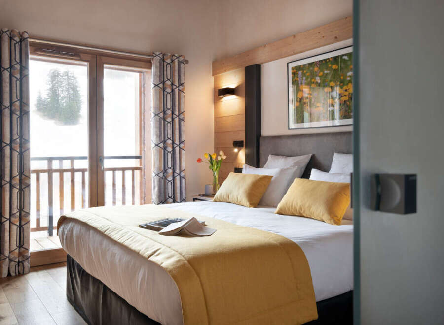 This luxurious bedroom boasts a king-size bed with plush bedding, a cozy yellow throw, and ample pillows for ultimate comfort.