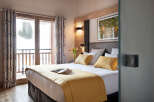 This luxurious bedroom boasts a king-size bed with plush bedding, a cozy yellow throw, and ample pillows for ultimate comfort.