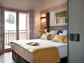 This luxurious bedroom boasts a king-size bed with plush bedding, a cozy yellow throw, and ample pillows for ultimate comfort.