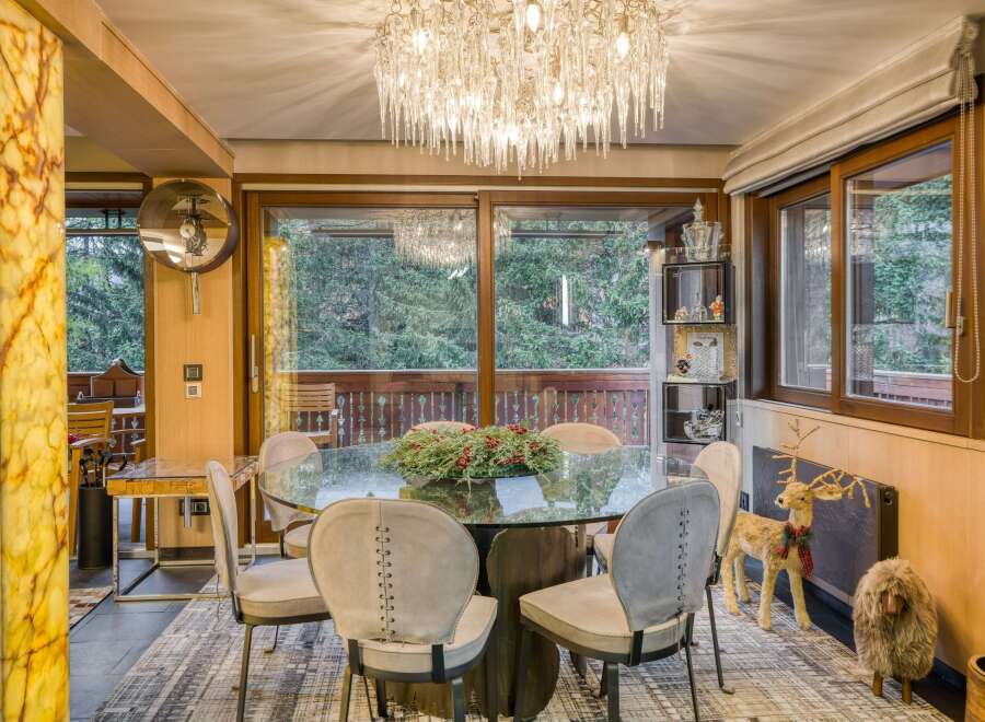 This stunning dining room boasts a glass-top table surrounded by six uniquely designed chairs, creating an elegant and modern ambiance.