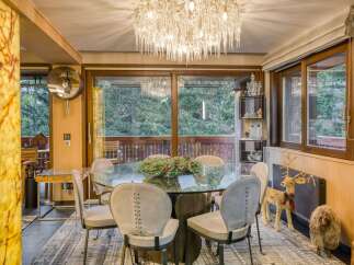 This stunning dining room boasts a glass-top table surrounded by six uniquely designed chairs, creating an elegant and modern ambiance.