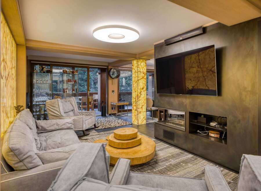 This luxurious living room boasts a stunning onyx feature wall, a modern fireplace, and comfortable gray sofas.