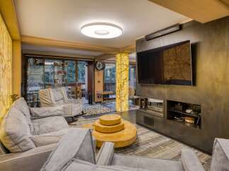 This luxurious living room boasts a stunning onyx feature wall, a modern fireplace, and comfortable gray sofas.