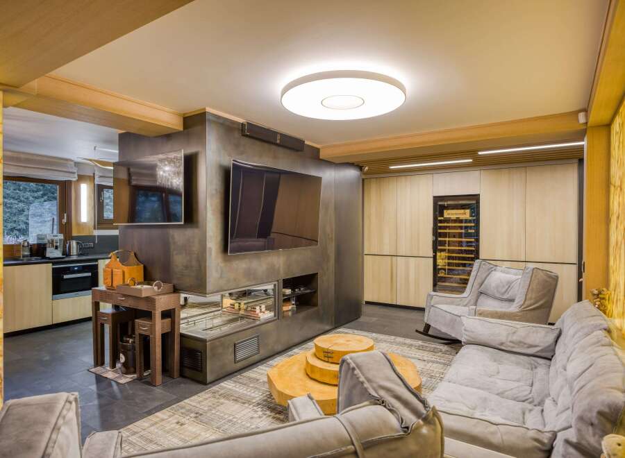 This stunning living room boasts a unique blend of rustic and modern design, featuring a sleek metal media wall with a built-in fireplace and a large flat-screen TV.
