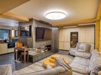 This stunning living room boasts a unique blend of rustic and modern design, featuring a sleek metal media wall with a built-in fireplace and a large flat-screen TV.