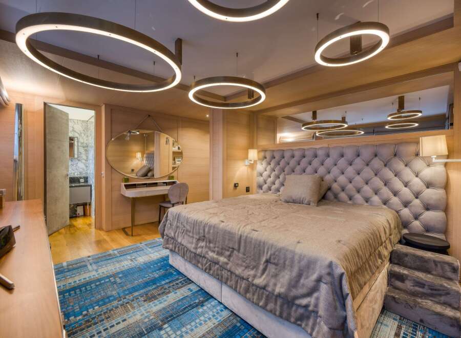 Luxurious bedroom with a plush upholstered headboard, complemented by a stylish oval mirror and a modern vanity.