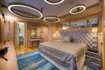 Luxurious bedroom with a plush upholstered headboard, complemented by a stylish oval mirror and a modern vanity.